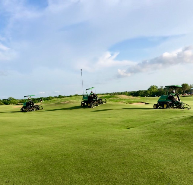 The John Deere fleet takes to the course to mow in between downpours. 